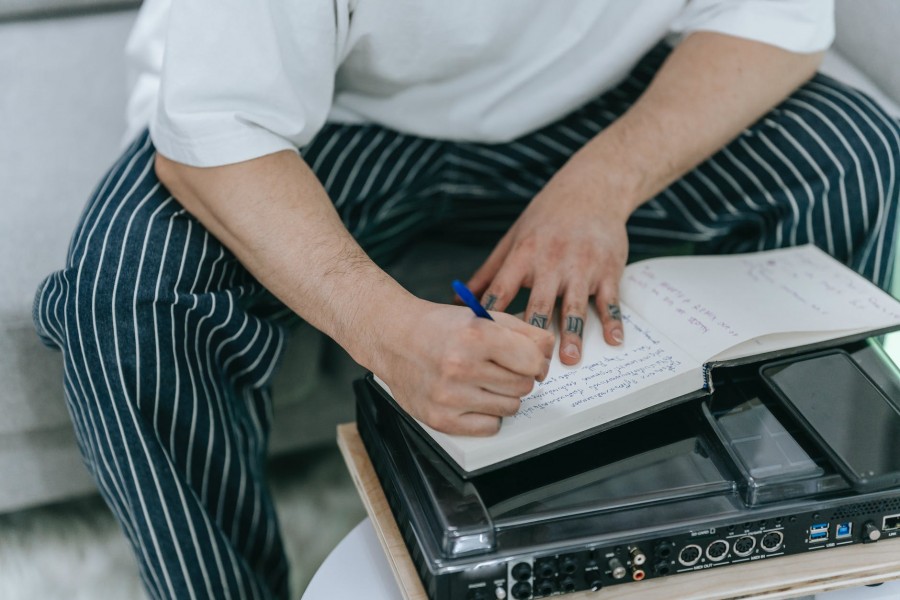 man in black and white strip pants writing notebook